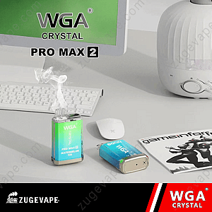 "Dispositivo per svapare WGA Crystal 6000 Pro Max 2 al gusto di anguria ghiacciata su una scrivania, che emette vapore accanto a una tastiera, un mouse e una rivista."