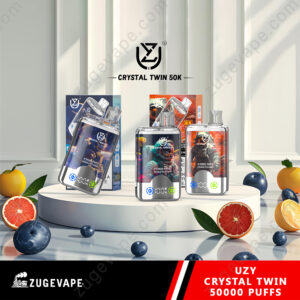 Promotional display of UZY Crystal Twin 50K vaping devices featuring colorful product packaging and fruits on a sleek white table under soft lighting.
